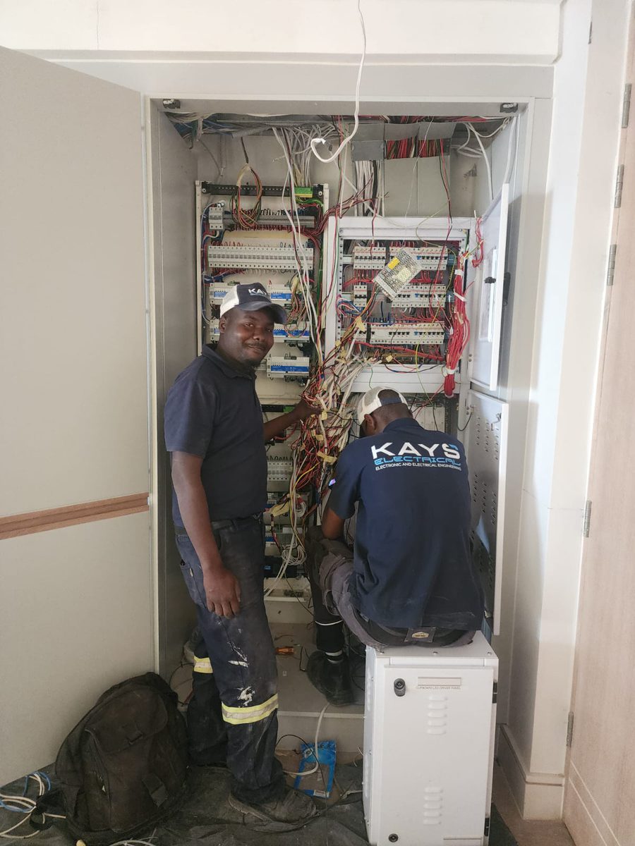 Two Kays Electrical electricians in branded uniform wiring a distribution board on site